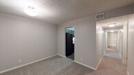 This single-floor residence offers a thoughtfully designed layout that balances functionality and comfort throughout its interconnected spaces. The kitchen is a standout feature, showcasing dark gray shaker-style cabinetry with brushed nickel hardware, light quartz countertops, a classic tile backsplash, and a full suite of black appliances including a range, over-the-range microwave, dishwasher, and refrigerator. Rich wood-look flooring grounds the kitchen and entry areas, creating a warm contrast against the neutral gray walls found throughout the unit. The living and dining areas are finished with plush carpet and textured ceilings, offering a comfortable and cohesive feel. Multiple bedrooms provide generous floor space, each carpeted and painted in soft gray tones, with windows that allow natural light to filter in. The bathrooms maintain a consistent design language, featuring gray cabinetry, quartz-style countertops, vessel sinks with brushed nickel faucets, and large mirrors. One bathroom includes a walk-in shower with tile surround, while the other features a tub. A dedicated entryway with wood-look flooring and easy access to adjoining rooms completes this well-organized, move-in-ready space.