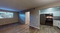 This single-story residence in Louisville, Kentucky offers a practical and well-appointed layout across two bedrooms and two bathrooms. The open living area features a combination of wood-style plank flooring and plush carpeting, with neutral gray walls and a textured ceiling throughout. Natural light filters in through a window, brightening the space, while a floor vent and wall thermostat indicate a dedicated climate control system.

The kitchen is a notable highlight, outfitted with white shaker-style cabinetry, dark granite countertops, a classic white subway tile backsplash, and stainless steel appliances including a refrigerator, range, and over-the-range microwave. A double-basin stainless steel sink with a brushed nickel faucet completes the functional workspace, all set on wood-style flooring.

Each bedroom is carpeted and features neutral gray walls, a ceiling fan with light fixture, and a closet with bifold doors providing organized storage. The bathrooms include a tub and shower combination with large-format marble-look tile surrounds and brushed nickel hardware, lending a clean, contemporary feel. Overall, the unit presents a cohesive, updated aesthetic suited for comfortable everyday living.