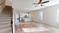 Located at 9913 Crescent Cove Dr in Montgomery, TX, this two-story home offers a thoughtfully designed layout with modern finishes throughout. The main level centers around a bright, open-concept living and kitchen area where light wood-look flooring, crown molding, and a ceiling fan create a welcoming atmosphere. Natural light streams through multiple windows fitted with blinds, illuminating the spacious living area. The kitchen is well-equipped with white shaker cabinetry extending to the ceiling, stainless steel appliances including a refrigerator, microwave, and range, and a granite-topped island with a built-in sink that doubles as a breakfast bar. Track and recessed lighting complete the kitchen's functional design. Bathrooms feature tile flooring, tiled tub-and-shower combinations, granite vanity countertops, and white cabinetry. Upper-level bedrooms are finished with plush carpet, vaulted ceilings with ceiling fans, ample natural light from multiple windows, and built-in closets with shelving. A compact powder room with a natural light window is also present. The staircase connects both floors in a clean, open layout, as revealed in the dollhouse view of the home's two-level structure.