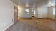 This single-floor residence offers a practical and well-organized layout connecting several distinct living spaces. The main living area features a combination of neutral-toned carpet and wood-look flooring, with a textured ceiling and multiple windows fitted with blinds that allow for natural light. A dedicated entryway door provides a clear front access point, while a second interior door leads to additional rooms.

The kitchen is efficiently designed, featuring white cabinetry with warm wood trim, light speckled countertops, and a full suite of stainless steel appliances including a refrigerator, electric range with overhead ventilation hood, and ample upper and lower cabinet storage. A pass-through window connects the kitchen to the main living area, enhancing the sense of openness.

The bedrooms are carpeted and finished with neutral walls and textured ceilings, each with window access to natural light. The primary bathroom offers an extended vanity with a white cabinet base, speckled countertop, and a large mirror, alongside a separate bathing area. A second full bathroom includes a tub/shower combination, wood-look flooring, and a vanity with matching countertop finishes. Wood-look flooring runs throughout the bathrooms and kitchen areas, providing a cohesive aesthetic across the unit.