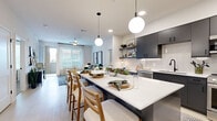 Located in Mesa, AZ, this well-designed single-floor residence offers three bedrooms, two bathrooms, and two closets within a thoughtfully organized floor plan. The open-concept kitchen and living area serves as the heart of the home, featuring dark charcoal cabinetry, white subway tile backsplash, stainless steel appliances, and a large center island with seating for multiple guests. Globe pendant lights hang above the island, adding a contemporary touch. Light-toned flooring flows throughout the main living area, complementing the bright, airy atmosphere created by abundant recessed lighting and natural light. The living room is connected to a private balcony through a glass door flanked by large windows dressed with sheer curtains and horizontal blinds, offering outdoor views and excellent natural light. The primary bedroom features soft carpet, a textured accent wall, and a window that fills the room with daylight. A walk-in closet with built-in shelving and hanging rods provides ample storage. The bathrooms are finished with neutral tile flooring, white subway-tiled tub surrounds, gray vanities, and matte black fixtures. Each space in this residence reflects a cohesive modern aesthetic, making it a comfortable and functional home.