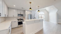 Located at 274 South Ave in Fanwood, NJ, this two-bedroom, two-bathroom two-story residence offers a well-appointed layout spread across two generously sized floors. The main level serves as the social hub of the home, featuring an open-concept kitchen and dining area equipped with gray shaker cabinetry, a subway tile backsplash, stainless steel appliances, and a center island with beadboard paneling beneath stylish pendant lighting. A striking arched window floods the adjacent living room with natural light, complementing the light-toned hardwood flooring that runs throughout. A private balcony extends the living space outdoors. A built-in mudroom with bench seating, coat hooks, and open shelving adds practical everyday functionality. The upper floor houses the spacious primary bedroom, complete with a large walk-in closet featuring custom built-in shelving and hanging rails. The second bedroom benefits from angled roofline ceilings that lend architectural character, along with a ceiling fan and ample natural light. Both bathrooms are finished with gray cabinetry and clean tile flooring. A dedicated laundry room with stacked washer and dryer units and an on-demand water heater, along with a utility room, round out the home's practical amenities. Seven total closets ensure exceptional storage throughout.