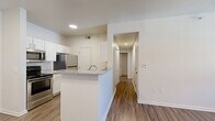 Located at 340 Shadow Ridge Grove in Colorado Springs, CO, this two-bedroom, three-bathroom residence offers a well-designed single-floor layout with a clean, modern aesthetic throughout. The open-concept kitchen and dining area serves as the heart of the home, featuring white shaker-style cabinetry, stainless steel appliances, granite countertops, and a peninsula island with a built-in sink — ideal for both meal preparation and casual dining. Wood-style plank flooring runs through the main living areas, complementing the bright, neutral color palette and recessed lighting overhead. The living room is a comfortable and airy space, highlighted by a ceiling fan with light fixture and a glass door leading to a private balcony. The balcony overlooks a landscaped community courtyard with mature trees and mountain sky views — a standout feature of this Colorado Springs location. Both bedrooms are carpeted and filled with natural light through vertical-blind-covered windows, with generous closet storage. Four closets total provide ample organization throughout. The three bathrooms each include tub/shower combinations with classic white tile surrounds. Additional conveniences include an in-unit laundry area and a central hallway connecting all rooms efficiently. This residence offers a practical and comfortable layout in a well-maintained community setting.