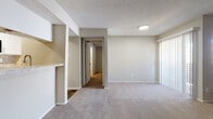 This single-floor residence offers a thoughtfully designed layout that balances comfort and functionality throughout. The living area serves as the heart of the home, highlighted by a classic tile-surround fireplace with a white wood mantel, soft wall-to-wall carpeting, and a textured ceiling. Vertical blinds and a large window allow natural light to fill the space, creating a warm and inviting ambiance. A built-in pass-through shelf connects the living area to the kitchen, which features wood-look vinyl flooring, subway tile backsplash, white cabinetry, and black appliances including a refrigerator, electric range, and over-the-range microwave. The bedrooms are generously sized, each equipped with ceiling fans, plush carpeting, and windows with blinds that frame views of the surrounding greenery. The primary bedroom includes a walk-in closet with built-in shelving for ample storage. The bathrooms are cleanly finished with wood-look flooring, white vanity cabinetry, stone-look countertops, framed mirrors, and a tiled shower-tub combination. A hallway connects the private quarters to the main living spaces, completing this comfortable and well-organized floor plan.