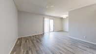 Located at 4337 N 53rd Ln in Phoenix, Arizona, this one-bedroom, one-bathroom unit offers a thoughtfully organized floor plan with consistent wood-look flooring throughout. The combined kitchen and living area forms the heart of the unit. The galley-style kitchen is well-appointed with white cabinetry, light quartz-style countertops, a grey subway tile backsplash, a stainless steel sink, dishwasher, refrigerator, and an electric range — providing ample functionality within a compact layout. The open living area features a sliding glass door with vertical blinds, allowing natural light to flow in while providing access to an outdoor area. A flush-mount light fixture adds overhead illumination, and textured ceilings are present throughout the unit. The bedroom is a comfortable size, featuring a window with blinds that brings in natural light, wood-look flooring, and direct access to two closets — one of which is a walk-in with built-in shelving. The full bathroom includes a tub/shower combo, a white vanity with cabinet storage, and wood-look tile flooring, maintaining a clean, bright aesthetic. The neutral grey tones and modern finishes across all rooms create a cohesive and move-in ready environment.