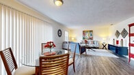 Located at 6403 Jamesville Dr in Tampa, FL, this single-floor home offers a thoughtfully designed layout with comfortable, interconnected living spaces. The open-concept living and dining area is anchored by wood-look laminate flooring, a textured ceiling, and large vertical-blind-covered sliding doors that draw in natural light. The living room provides ample space for seating arrangements and features multiple windows overlooking the surroundings, creating a bright and welcoming atmosphere.

The dining area flows seamlessly from the living room and sits adjacent to the kitchen, which is outfitted with white cabinetry, light countertops, a double-basin sink beneath a window, and white appliances including a range, microwave, dishwasher, and refrigerator. A breakfast bar with counter seating connects the kitchen to the main living area, making it ideal for casual dining.

The primary bedroom is generously sized with plush carpeting, a walk-in closet, and direct access to an en-suite bathroom featuring a walk-in shower. A second bedroom also offers carpet flooring and a standard closet with convenient hallway access. A second bathroom with a standalone shower stall serves the rest of the home. The overall ambiance is light, airy, and inviting throughout.
