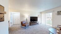 Located at 3121 Village Ct in Janesville, Wisconsin, this single-floor residence offers a practical and comfortable layout across four distinct rooms. The living room serves as the heart of the home, featuring plush carpeting, a sliding glass door that invites natural light and outdoor views, and a wall-mounted air conditioning unit for year-round comfort. The space is open and airy, providing ample room for relaxing and entertaining. The galley-style kitchen is efficiently designed with white cabinetry, granite-look countertops, black appliances including a range, microwave, refrigerator, and dishwasher, all set atop durable tile flooring that adds a warm, earthy tone. The bedroom is a serene retreat, carpeted throughout and equipped with a ceiling fan with light fixture, a natural window view, and convenient access to a walk-in closet. The full bathroom continues the tile flooring found in the kitchen and features a shower/tub combination with a classic curtain, a vanity with storage, and clean, neutral finishes. Throughout the residence, the neutral color palette and consistent design choices create a cohesive and welcoming ambiance well-suited for comfortable everyday living.