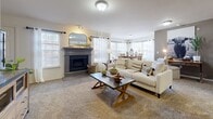This single-floor residence offers a thoughtfully designed layout with a comfortable and cohesive aesthetic throughout. The living room serves as the heart of the home, featuring a classic fireplace with a decorative mantle, plush carpeting, and multiple windows dressed with sheer curtains and blinds that allow generous natural light to fill the space. The open flow connects the living area to a bright dining space, which is surrounded by large windows on multiple sides, creating an airy and sunlit atmosphere ideal for everyday meals or entertaining.

The kitchen is outfitted with rich dark cabinetry, light granite-style countertops, a peninsula for additional prep or seating, and a full suite of stainless steel appliances including a refrigerator with water and ice dispenser, electric range, built-in microwave, and sink. Large-format tile flooring adds a clean, durable finish to the space.

The bedrooms are carpeted and comfortably sized, each featuring ceiling fans and windows with natural light. The rooms offer ample space for full furniture arrangements and provide a calm, restful environment.

The bathrooms are finished with tile flooring and tiled tub-shower combinations, offering clean and functional design. Dark cabinetry mirrors the kitchen's aesthetic, providing a consistent design language throughout the home.