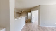 Located at 1010 NW Fresco Way in Stuart, Florida, this single-floor residence offers four bedrooms and one bathroom within a thoughtfully arranged layout. Light wood-style flooring runs throughout the home, lending a clean, cohesive aesthetic to every room.

The open-concept living and dining area is bright and airy, with neutral warm-gray walls and a sliding glass door that opens to a private patio with outdoor greenery views. The kitchen features a raised breakfast bar that separates it from the living space, light wood cabinetry, white countertops, and a full suite of stainless steel appliances including a refrigerator, electric range, and over-the-range microwave. The kitchen benefits from soaring vaulted ceilings and a multi-bulb track light fixture that adds contemporary style. An in-unit washer and dryer area is also visible adjacent to the kitchen.

The four bedrooms are accessed via a central hallway, each featuring the same light flooring and neutral walls. The primary bedroom is a comfortable size, while additional bedrooms offer flexible use as guest rooms, offices, or more. Windows allow natural light and outdoor views into the rooms.

The single bathroom includes a white tile tub-shower combination, toilet, and wood-style flooring, finished with brushed nickel grab bars and accessories for a clean, functional design.