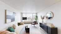 Located in Oakland, CA, this 2-bedroom, 1-bathroom residence offers a well-designed layout with modern finishes throughout. The open living room is a standout feature, anchored by expansive floor-to-ceiling windows that frame sweeping panoramic views of the Oakland skyline, flooding the space with natural light. Light-toned wood-style flooring runs throughout the main living areas, adding warmth and continuity.

The kitchen is efficiently designed with gray flat-front cabinetry, stainless steel appliances including a refrigerator and microwave, a mosaic tile backsplash, and a white quartz breakfast bar with seating — ideal for casual dining and entertaining.

The primary bedroom is generously proportioned, featuring large windows with the same impressive city views, plush carpeting, and full-width mirrored sliding closet doors that enhance the sense of space. The second bedroom offers carpeted flooring and a clean, versatile layout suitable for a variety of uses.

The bathroom is finished with a wide vanity featuring gray cabinetry, a white countertop, a large mirror, light wood-style flooring, and a full shower-tub combo. Clean white walls and thoughtful details complete the space, creating a cohesive and comfortable urban residence.