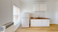 Located at 744 Beacon Avenue in Los Angeles, CA, this single-floor studio unit offers a clean, functional layout with a thoughtfully designed interior. Light hardwood flooring runs throughout the space, complementing the crisp white walls and creating a bright, cohesive aesthetic.

The kitchen is a standout feature, outfitted with white shaker-style cabinetry above and below, a classic white subway tile backsplash, and a warm wood-toned countertop that adds a touch of contrast. A gas cooktop, double-basin sink, and full-size refrigerator provide all the essential amenities. Two windows fitted with horizontal blinds allow natural light to fill the kitchen and main living area, offering views of the surrounding neighborhood.

The main living area is open and versatile, featuring a built-in closet with a hanging rod, clean white walls, and ample natural light. The entry area connects seamlessly to both the living space and the bathroom, maintaining an efficient flow throughout the unit.

The bathroom is compact and cleanly finished, featuring an all-white stand-up shower stall with chrome fixtures and a wall-mounted sink. The minimalist design keeps the space feeling fresh and orderly. Overall, the unit offers a practical and well-maintained environment suited for single occupancy in the heart of Los Angeles.