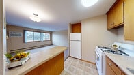Located at 6301 Lyndale Ave S in Richfield, MN, this one-bedroom, one-bathroom unit offers a practical and efficiently organized floor plan. The layout connects each room through a central hallway, providing a clear and logical flow throughout the space.

The living room is carpeted and receives natural light through a pair of large sliding windows with warm wood-toned trim, offering views of the surrounding neighborhood. Baseboard heating and a wall-mounted air conditioning unit ensure year-round comfort.

The kitchen features warm oak cabinetry both above and below the counters, providing ample storage. A gas range, refrigerator, and double sink make up the functional appliance suite, while light tile flooring completes the space. A peninsula counter connects the kitchen to the adjacent living area.

The bedroom is a well-proportioned, carpeted room with a set of sliding wood-panel closet doors offering generous storage. A window allows natural light to filter in, and baseboard heating keeps the room comfortable.

The bathroom includes a tiled tub/shower combination, a wood-vanity with sink, a window for ventilation and natural light, and warm-toned tile flooring. A hallway with tile flooring connects the main rooms and provides access throughout the unit.