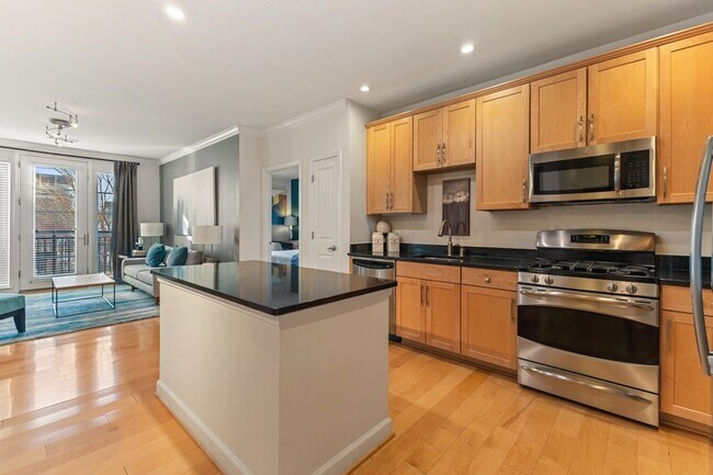 Gourmet kitchens with wood cabinets, granite countertops, and stainless steel appliances - The Reserve at Tysons Corner