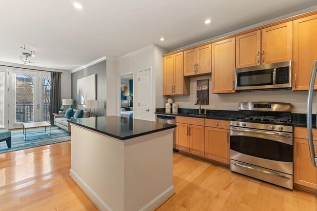 Gourmet kitchens with wood cabinets, granite countertops, and stainless steel appliances - The Reserve at Tysons Corner