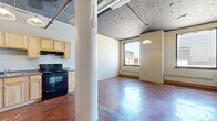 Located at 344 Wabasha St N in downtown Saint Paul, this one-bedroom, one-bathroom unit showcases a distinctive urban loft aesthetic throughout. Rich, polished concrete floors in a warm terracotta hue run continuously across the entire space, lending an industrial yet inviting character to every room.

The open living and dining area is anchored by a large window that frames views of the surrounding downtown skyline, filling the space with natural light. An exposed ceiling with visible ductwork and decorative tin-style detailing reinforces the industrial character, while a structural column adds architectural interest to the main living zone.

The kitchen is well-appointed with light maple cabinetry, dark countertops, and black appliances including a refrigerator, electric range, and built-in microwave. Pendant lighting overhead adds a warm, functional touch.

The bedroom is a comfortable, private retreat with its own large window offering additional city views, a ceiling fan, and a spacious sliding-door closet for ample storage.

The bathroom features a light maple vanity with under-sink storage, a wall-mounted mirror with overhead lighting, and a tub-shower combination. The same polished concrete flooring carries through, maintaining a cohesive look across the entire unit.