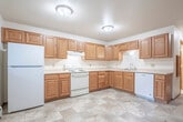 Located at 3620 Patti Dr in Plover, Wisconsin, this single-story home offers a practical and comfortable layout across four bedrooms and two bathrooms. The kitchen serves as a functional centerpiece, featuring warm oak cabinetry with ample storage, light countertops in an L-shaped configuration, a white electric range, a dishwasher, and a double basin sink. The tile flooring extends through the kitchen and into the entry area, which includes a side door with a window, a closet, and a baseboard heating unit. The spacious primary bedroom provides generous room for furnishings, while the additional bedrooms are finished with neutral carpet and wood-trimmed doors, offering a clean and versatile living space. The full bathroom includes a tub-shower combination, while the second bathroom features a dual-sink oak vanity with a large mirror and tile flooring, conveniently positioned adjacent to the dedicated laundry room, which houses a full-size washer and dryer with built-in shelving. Baseboard heating is present throughout the home, and consistent wood trim detailing ties the interior together with a cohesive, understated aesthetic.