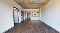 Located at 1828 N Farwell Ave in Milwaukee, Wisconsin, this contemporary urban residence showcases an industrial-modern aesthetic defined by exposed concrete ceilings and rich, dark hardwood flooring throughout. The open-concept living area is bright and spacious, seamlessly connecting to a well-appointed kitchen featuring granite countertops, white cabinetry, subway tile backsplash, stainless steel appliances, and stylish pendant lighting over a breakfast bar peninsula. The living space extends to a private balcony accessed through floor-to-ceiling glass doors, offering sweeping views of the Milwaukee cityscape. Bedrooms are generously sized, each benefiting from natural light through large windows with urban views, exposed concrete ceilings, and wall-mounted climate control units. A dedicated laundry closet with a stacked washer and dryer provides added convenience. The bathroom is clean and modern, complete with a walk-in shower, granite vanity, and white cabinetry. Throughout the unit, the interplay of raw industrial elements and refined finishes creates a cohesive, contemporary atmosphere suited to urban living.