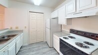 Located at 1890 Cathedral Mills Ln. in Rock Hill, South Carolina, this single-floor residence offers a thoughtfully arranged layout designed for comfortable everyday living. The living area is bright and welcoming, featuring durable wood-look laminate flooring, a ceiling fan with light fixture, and multiple windows dressed with blinds that allow generous natural light to filter in. A set of double doors opens to the exterior, further enhancing the connection to the outdoors. The kitchen is accessible via a pass-through counter opening, creating an open, connected feel between the cooking and dining spaces. It is equipped with white cabinetry, granite-style countertops, a coil-burner electric range, a full-size refrigerator, and easy-care laminate flooring. A set of bi-fold doors provides additional storage or pantry space. The bedrooms are finished with plush wall-to-wall carpet and feature dedicated closets with built-in shelving rods, offering practical storage solutions. Windows in the bedrooms bring in natural light and outdoor views. The bathroom is cleanly appointed with a single-sink vanity topped with a speckled countertop, white cabinetry below, a large mirror with overhead lighting, and a full-size soaking tub with shower combination. Neutral tones and a textured ceiling are consistent throughout the space, creating a cohesive and move-in ready environment.