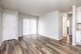 This single-floor residence offers a practical and comfortable layout with a consistent design aesthetic carried throughout. Warm-toned hardwood-style flooring runs continuously across all rooms, creating a cohesive and easy-to-maintain living environment. Neutral white walls and textured ceilings contribute to a bright, clean atmosphere.

The living area is generously proportioned, featuring a large sliding glass door dressed with vertical blinds that allows ample natural light to fill the space. A ceiling fan with integrated lighting provides comfort and airflow, while a wall-mounted mini-split HVAC unit ensures efficient climate control. The open layout connects seamlessly to the kitchen area.

The kitchen is well-appointed with white cabinetry offering substantial storage, light granite-style countertops, a double-basin stainless steel sink, and white appliances including an electric range and refrigerator. A dishwasher is also present beneath the counter.

The bedrooms are comfortably sized, each featuring the same hardwood-style flooring and windows fitted with horizontal blinds that provide natural light and privacy. The rooms offer a neutral, versatile backdrop suitable for a variety of furnishing arrangements.

The bathroom is finished with a white vanity topped with matching granite-style countertops, a single-basin sink, a full tub-shower combination, and continued hardwood-style flooring, maintaining the home's cohesive design throughout.