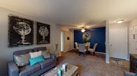 Located in Rolling Hills, this single-floor residence offers a well-organized and functional layout across multiple rooms. The open-concept living and dining area serves as the heart of the home, featuring plush carpeting, a textured ceiling, and a ceiling fan overhead. A bold navy accent wall anchors the dining space, creating a striking visual contrast against the neutral gray tones of the living area. Large windows allow natural light to fill the space, enhancing its warm and welcoming ambiance.

The kitchen is equipped with gray cabinetry, dark countertops, and black appliances including a refrigerator, dishwasher, and range. Wood-look flooring and a window above the sink add both practicality and brightness to the space.

The primary bedroom is generously sized, featuring plush carpet, multiple windows with blinds and curtains, and ample room for a full furniture arrangement. The second bedroom is versatile, offering space for both a bed and a dedicated desk area, making it suitable as a guest room or home office. A closet with bi-fold doors provides convenient storage.

Two bathrooms complete the layout. One features wood-look flooring, a shower-tub combination, and clean white tilework. The other includes a vanity with gray cabinetry, a well-lit mirror, and wood-look flooring, offering a polished and functional finish throughout.