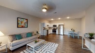 Located at 2210 Charlestown Rd in New Albany, Indiana, this single-floor residence offers a well-designed, open-concept layout that seamlessly connects the living, dining, and kitchen areas. Rich hardwood-style flooring runs throughout the main living spaces, complementing the neutral gray walls and recessed lighting that create a bright, welcoming ambiance. The living room features a ceiling fan, a sliding glass door that floods the space with natural light and provides access to an outdoor area, making it an ideal spot for relaxing or entertaining.

The kitchen is outfitted with crisp white shaker cabinetry, granite-style countertops, and a full suite of stainless steel appliances, including a gas range, microwave, and refrigerator. Adjacent to the kitchen, a dedicated dining area provides a comfortable space for meals.

The bedrooms are carpeted for comfort, each featuring ceiling fans and windows that invite natural light. The primary bedroom includes access to a spacious walk-in closet with wire shelving for ample storage. The bathroom is finished with a white vanity, generous counter space, and wood-style flooring that ties the design together cohesively.

A dedicated utility room houses the water heater and provides washer/dryer hookups, adding everyday convenience. Overall, the space delivers a clean, modern aesthetic suited for comfortable single-level living.