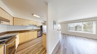 Located in Shoreline, WA, this 2-bedroom, 1-bathroom residence offers a practical and well-appointed single-level layout. The open-concept kitchen and living area form the heart of the home, connected by a pass-through counter. The kitchen features light maple cabinetry, dark granite-style countertops, stainless steel appliances including a refrigerator, dishwasher, and range, all set over durable wood-style flooring. The spacious living room is bathed in natural light from large windows and a sliding glass door, offering views of the surrounding neighborhood and treetops. Both bedrooms are carpeted and comfortably sized, each with windows that invite natural light. The primary bedroom includes access to a generous walk-in closet outfitted with wire shelving. The second bedroom features a standard closet with sliding doors. The full bathroom includes a wood-toned vanity with a granite-style countertop, a mirrored medicine cabinet, and a shower-tub combination. The consistent use of neutral tones, clean lines, and wood-style flooring throughout creates a cohesive and functional living environment well-suited for everyday comfort.