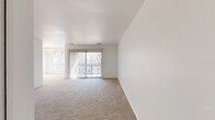 Located at 8732 Town and Country Blvd in Ellicott City, MD, this 1-bedroom, 1-bathroom residence offers a thoughtfully arranged single-floor layout designed for comfortable everyday living. The spacious living room is bathed in natural light, thanks to large sliding glass doors fitted with vertical blinds that open directly onto a private balcony — an ideal spot to enjoy outdoor views. Soft wall-to-wall carpeting extends throughout the living areas and bedroom, lending a warm, cohesive feel to the interior. The open layout seamlessly connects the living room to the dining area, while a separate kitchen features warm wood-toned cabinetry. The generously sized bedroom benefits from natural light through a large window and includes access to two closets, one of which is a walk-in with built-in shelving and hanging rods for ample storage. The full bathroom is finished with white tile flooring, a tub-shower combination, and a wood-vanity with a clean white countertop. A connecting hallway ties the rooms together efficiently. The clean, neutral palette throughout creates a bright, move-in-ready environment well-suited to a variety of living styles.