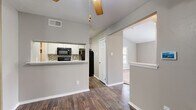 This single-story, 2-bedroom, 1-bathroom residence offers a thoughtfully designed layout that maximizes functionality and comfort. The kitchen is equipped with black Whirlpool appliances — including an electric range, over-the-range microwave, and dishwasher — paired with crisp white cabinetry, light quartz countertops, and a mosaic tile backsplash. A pass-through counter opening connects the kitchen to the main living area, promoting an open, communal feel. Rich hardwood-style flooring runs throughout the main living spaces and kitchen, adding warmth and continuity.

The living room features vaulted ceilings, a ceiling fan, natural light from multiple windows with blinds, and a white tile-surround fireplace as a central focal point, complemented by soft carpeting underfoot. Both bedrooms are carpeted and well-lit with natural light. The primary bedroom includes a dedicated closet and ample wall space, while the second bedroom features a mirrored sliding-door closet. The spacious bathroom offers a dual-sink vanity with white cabinetry, a large wall mirror, and hardwood-style flooring. A hallway connects the key rooms, completing this efficiently designed and move-in-ready home.