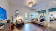 This single-floor residence offers a well-designed layout that balances open communal spaces with private retreats. The living area serves as the heart of the home, featuring wood-look flooring, a decorative ceiling fixture, and a teal accent wall that adds a pop of color. A glass door opens directly to an outdoor patio, while multiple windows dressed with sheer curtains and blinds allow natural light to filter in, offering views of surrounding greenery.

The kitchen is thoughtfully appointed with gray shaker-style cabinetry, white quartz countertops, a hexagonal tile backsplash, and a full suite of stainless steel appliances. A peninsula with a breakfast bar provides additional prep and seating space, and the layout flows seamlessly into a dining area brightened by a large window.

Both bedrooms are generously proportioned, with wood-look flooring and ample wall space. One bedroom features direct access to a private bathroom with gray cabinetry, a white vanity top, and a shower-tub combination. A second full bathroom mirrors this aesthetic, maintaining consistency throughout. The overall ambiance is modern and inviting, with clean lines and contemporary finishes.