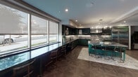 Located at 330 Westlake Ave in the Echo Park neighborhood of Los Angeles, this single-floor space presents a thoughtfully curated interior with a strong design identity. The open layout flows seamlessly between functional zones, each defined by distinctive finishes and furnishings.

The kitchen is a standout centerpiece, outfitted with deep forest green cabinetry, dramatic veined marble countertops and backsplash, and professional-grade stainless steel appliances including a large range with a commercial hood. A marble-topped island with gold-accented bar seating anchors the space, while a window-facing bar counter with sleek stools invites casual dining with natural light streaming in.

Adjacent to the kitchen, a private dining nook features rich cognac leather tufted banquette seating set against deep emerald green paneled walls, illuminated by a globe pendant light — an intimate and visually striking retreat within the larger space.

The lounge area offers generous seating with tufted gray sofas, a cognac leather accent chair, and layered area rugs atop warm parquet-style tile flooring. Recessed lighting, curated wall art, and lush indoor plants contribute to a polished yet welcoming ambiance. Large windows bring in natural light, and a sizable mounted display screen adds a media-ready dimension to the living area. Throughout, the design balances bold color choices with refined materials for a cohesive, upscale aesthetic.