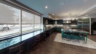 Located at 330 Westlake Ave in the Echo Park neighborhood of Los Angeles, this single-floor space presents a thoughtfully curated interior with a strong design identity. The open layout flows seamlessly between functional zones, each defined by distinctive finishes and furnishings.

The kitchen is a standout centerpiece, outfitted with deep forest green cabinetry, dramatic veined marble countertops and backsplash, and professional-grade stainless steel appliances including a large range with a commercial hood. A marble-topped island with gold-accented bar seating anchors the space, while a window-facing bar counter with sleek stools invites casual dining with natural light streaming in.

Adjacent to the kitchen, a private dining nook features rich cognac leather tufted banquette seating set against deep emerald green paneled walls, illuminated by a globe pendant light — an intimate and visually striking retreat within the larger space.

The lounge area offers generous seating with tufted gray sofas, a cognac leather accent chair, and layered area rugs atop warm parquet-style tile flooring. Recessed lighting, curated wall art, and lush indoor plants contribute to a polished yet welcoming ambiance. Large windows bring in natural light, and a sizable mounted display screen adds a media-ready dimension to the living area. Throughout, the design balances bold color choices with refined materials for a cohesive, upscale aesthetic.