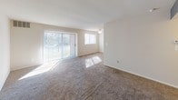 This single-floor residence offers a practical and comfortable layout designed to maximize livability. The living area is generously sized, finished with plush carpeting and neutral-toned walls, including a subtle blue accent wall that adds a touch of character. Large sliding glass doors and an adjacent window flood the space with natural light while providing direct access to the outdoors, creating a bright and welcoming atmosphere.

The kitchen is efficiently arranged with warm honey-toned wood cabinetry, dark speckled countertops, a stainless steel sink, and a gas range, providing ample storage and workspace for everyday cooking needs. Hard flooring in the kitchen adds durability and easy maintenance.

The bedroom is a spacious, carpeted retreat featuring a window with blinds for natural light and privacy. A notable feature is the double closet with bifold doors, offering generous built-in storage with dual hanging rods and shelving. The neutral color palette throughout creates a calm, cohesive feel.

The bathroom includes a full soaking tub and shower combination, framed by large neutral tiles accented with a decorative mosaic border. Chrome fixtures and wood-look flooring complete the clean, functional design of the space.