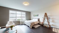 Located at 22 Sussex St in Hackensack, NJ, this single-floor residence offers a thoughtfully designed layout with a cohesive modern aesthetic throughout. The living area is anchored by warm taupe-toned accent walls, dark hardwood flooring, and a curated seating arrangement featuring a light linen sofa, brass-accented side tables, and a glass-top coffee table — creating an inviting, refined atmosphere. Framed wall art adds a finishing touch to the space.

The bedroom is generously proportioned, benefiting from a large multi-pane window that draws in natural light and provides views of the surrounding area. Dark hardwood floors continue here, complemented by a neutral color palette, a ladder-style shelving unit, and a flush-mount brass ceiling fixture.

The kitchen is outfitted with stainless steel appliances including a gas range and over-the-range microwave, two-tone cabinetry in white and wood-grain finishes, light countertops, and a subway tile backsplash — combining functionality with a clean, contemporary look.

The bathroom features a wall-mounted vanity with an LED-backlit mirror, a soaking tub with a wood-panel tile surround, white subway tile walls, and a distinctive pebble-stone floor, delivering a spa-inspired finish.