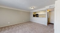 This single-floor residential unit offers a well-organized layout that balances open-concept living with functional, defined spaces. The living room is generously sized, featuring plush wall-to-wall carpeting, crown molding, a textured ceiling, and neutral-toned walls that create a clean, versatile backdrop. A wood-burning fireplace serves as a focal point on one wall, while a large sliding glass door fitted with vertical blinds fills the room with natural light and provides access to the exterior. The kitchen connects to the living area via a raised pass-through counter, allowing for easy interaction between spaces. It is equipped with black appliances, including an electric range, over-the-range microwave, and refrigerator, complemented by white cabinetry, granite-look countertops, and wood-style flooring. A dedicated laundry area houses a full-size side-by-side washer and dryer with overhead shelving for added storage. The bedroom is a comfortable, carpeted room with a ceiling fan and a window fitted with blinds that allow natural light. The bathroom includes a full tub-shower combination with tiled surround, a toilet, and wood-style flooring, maintaining a clean and functional design throughout.