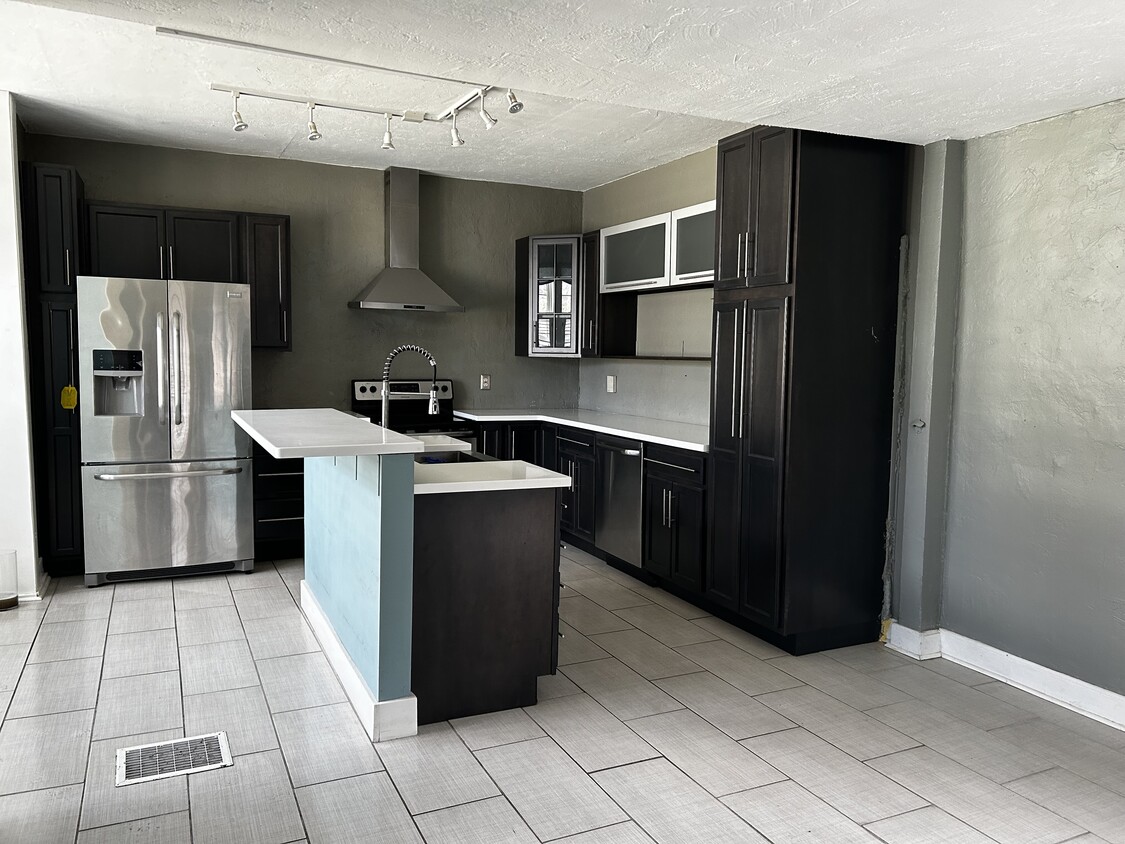 Spacious kitchen with modern cabinets, stainless steel appliances, and new tile flooring. - 916 Logan St