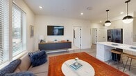 Located at 3806 University Drive in Durham, NC, this well-appointed 2-bedroom, 1-bathroom residence offers a thoughtfully designed single-floor layout. The open-concept kitchen and living area serves as the heart of the home, where light-toned flat-panel cabinetry, a large center island with bar seating, white quartz countertops, and stainless steel appliances create a sleek, modern kitchen. Stylish globe pendant lights hang above the island, adding a contemporary touch. Light wood-look flooring flows throughout the main living areas, seamlessly connecting the kitchen to a bright and comfortable living room that benefits from natural light through large windows with outdoor views. Both bedrooms feature plush carpeting, ceiling fans, and generous windows that bring in natural light. The spacious primary bedroom includes a large walk-in closet outfitted with wire shelving and hanging systems, providing ample storage. A second closet serves the additional bedroom. The full bathroom is finished with a tiled tub-shower combination, black hardware accents, and wood-look tile flooring. Recessed lighting throughout maintains a clean, modern aesthetic, while the open flow between spaces enhances the overall sense of roominess and functionality.