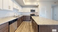 Located at 1001 Beringer Rd in Suffolk, Virginia, this single-floor residence offers a thoughtfully designed layout with modern finishes throughout. The kitchen serves as a standout feature, boasting two-tone cabinetry with white upper cabinets and dark lower cabinets, granite countertops, stainless steel appliances, a center island with pendant lighting, and wood-look luxury vinyl plank flooring. A tray ceiling adds an architectural touch that elevates the space.

The living area is generously sized, featuring plush wall-to-wall carpeting, a ceiling fan, and a sliding glass door that invites natural light and provides outdoor access. The neutral color palette creates a bright, open ambiance throughout the home.

The bedrooms are carpeted and well-proportioned, each offering closet storage. One bedroom features dual closets, while another includes a spacious walk-in closet outfitted with wire shelving for organized storage.

The bathrooms are finished with granite-topped white vanities, wood-look vinyl flooring, and brushed nickel hardware. One bathroom includes a tiled tub-shower combination, while another features a dedicated vanity area. Clean white walls and consistent finishes lend a cohesive, modern feel across all bathrooms.