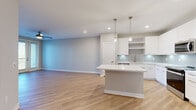 Located on International Drive in Orlando, Florida, this well-appointed 1-bedroom, 1-bathroom unit offers a thoughtfully designed open-concept layout with modern finishes throughout. Light wood-look flooring flows seamlessly across the main living areas, creating a bright and cohesive aesthetic.

The kitchen is a true standout, featuring crisp white cabinetry, a subway tile backsplash, stainless steel appliances, and a large center island with a white quartz countertop, illuminated by elegant pendant lights. The kitchen opens directly into the spacious living area, which benefits from natural light streaming through French doors that lead to a private balcony. A ceiling fan adds both comfort and style to the living space.

The generously sized primary bedroom is finished with plush carpeting, a ceiling fan, and a window offering pleasant outdoor views. Two closets provide ample storage. The bathroom is elegantly appointed with a wide white vanity, framed mirrors with modern lighting fixtures, and a glass-enclosed walk-in shower with tile surround.

Neutral-toned walls throughout the unit create a clean, versatile backdrop, while recessed lighting and contemporary fixtures elevate the overall ambiance. This unit combines functional design with modern style in a prime Orlando location.