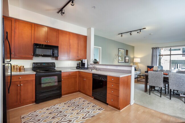Paquete Clásico I: cocina con electrodomésticos negros o blancos, gabinetes de cerezo, encimeras laminadas y pisos de superficie dura. - Avalon at Cahill Park
