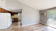 Located at 5546 Scranton Rd in Hamburg, NY, this one-bedroom, one-bathroom unit offers a practical and efficient layout across a single floor. The open living and dining area is finished with light wood-look flooring and neutral gray walls, creating a clean, understated aesthetic. A wall-mounted air conditioning unit and baseboard heating provide year-round climate control. A sliding glass door brings in natural light and offers outdoor views, while a modest chandelier adds a touch of character to the dining space. The kitchen is equipped with dark wood cabinetry, a tile backsplash, a white electric range, refrigerator, and a dishwasher, providing essential functionality in a compact footprint. The bedroom is a comfortable, well-proportioned space with wood-look flooring, baseboard heating, and a window overlooking the greenery outside, allowing for ample natural light. The bathroom features classic yellow ceramic tile lining the tub surround and walls, a full bathtub with shower, a window for ventilation, and baseboard heating. Throughout the unit, consistent flooring and a cohesive neutral color palette contribute to a tidy, move-in ready feel suited for everyday living.