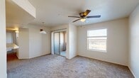 This single-floor, 2-bedroom, 2-bathroom home offers a practical and comfortable layout designed for everyday living. The generously sized primary bedroom is a standout feature, occupying a significant portion of the home's total footprint. It is carpeted throughout, filled with natural light from a large window with blinds, and equipped with a ceiling fan. A sliding glass-door closet and access to a spacious walk-in closet with multi-level shelving and hanging rods provide ample storage. The second bedroom mirrors a similar design with carpet flooring, a ceiling fan, a window with blinds, and a mirrored sliding closet door. The kitchen is well-equipped with warm honey-toned wood cabinetry, light countertops, tile flooring, and black appliances including a gas range, over-the-range microwave, and refrigerator. Both bathrooms feature tile flooring, with one showcasing a full tub-shower combo and a rich wood-toned vanity. A dedicated laundry room with side-by-side washer and dryer hookups and overhead shelving adds everyday convenience. The home's neutral color palette and consistent finishes create a clean, cohesive ambiance throughout.