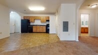 Located at 1220 N King Street in Hampton, Virginia, this single-floor unit offers a well-organized layout designed for comfortable everyday living. The kitchen is equipped with warm honey-toned wood cabinetry extending to the ceiling, dark countertops, a double-basin sink, and black appliances including a refrigerator and dishwasher, all set atop stone-look tile flooring. An arched architectural detail connects the kitchen to the adjacent living and dining areas, where the same tile flooring transitions seamlessly into plush carpeting throughout the rest of the unit. The living area is open and bright, with natural light filtering in through blinds-fitted windows. Multiple bedrooms feature soft wall-to-wall carpeting, generous windows with outdoor views of the surrounding neighborhood, and ample closet space. One bedroom includes a dedicated utility closet. The unit features two bathrooms, each finished with stone-look tile flooring and warm wood vanities with light countertops and mirrored medicine cabinets. One bathroom includes a walk-in shower stall with grab bars. Throughout the unit, neutral white walls, visible HVAC vents, and consistent trim work provide a clean, cohesive aesthetic that is both practical and inviting.