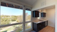 Located on the third floor at 215 Vista Village, Unit #306 in Vista is a thoughtfully designed residence that blends contemporary finishes with an airy, open feel. The living area is expansive and bright, featuring light-toned luxury vinyl plank flooring, crisp white walls, and large floor-to-ceiling windows that frame lush treetop views and flood the space with natural light. The galley-style kitchen is well-appointed, featuring dark espresso cabinetry, marble-look quartz countertops, stainless steel appliances including a refrigerator, microwave, and range, as well as a stainless steel sink positioned beneath a window overlooking the greenery outside. The bedrooms are comfortably sized with the same light wood-style flooring, ceiling fans, generous windows for natural light and outdoor views, and ample closet space with built-in shelving. The bathroom is finished with a marble-look vanity countertop, dark cabinetry, a large mirror with vanity lighting, and a full shower-tub combination with clean white tile surround. Throughout the unit, clean lines, neutral tones, and modern hardware create a cohesive and move-in-ready aesthetic suited for comfortable everyday living.