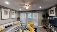 This single-story 1-bedroom, 1-bathroom residence offers a well-organized and efficiently designed floor plan with cohesive modern finishes throughout. The living room serves as the heart of the space, featuring wood-look flooring, a ceiling fan with light fixture, recessed lighting, a textured ceiling, and large windows complemented by a sliding glass door with vertical blinds that invite natural light and provide access to the outdoors. The kitchen is a standout feature, boasting granite countertops, dark cabinetry, a stainless steel double-basin sink, and black appliances including a refrigerator and range. Wood-look flooring continues through the kitchen, enhancing its clean, contemporary aesthetic. The bedroom is a comfortable retreat finished with plush carpet, a ceiling fan, and a mirrored sliding closet that adds a sense of depth and space. Natural light filters in through a window with blinds, and a doorway connects directly to the bathroom. The bathroom is neatly designed with a granite-topped vanity featuring dark cabinetry, wood-look flooring, and a full tub-shower combination. Warm, neutral tones and consistent design elements tie the entire space together, creating a cohesive and inviting atmosphere throughout.