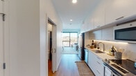 Located at 2250 University Ave W in Saint Paul, Minnesota, this thoughtfully designed single-floor residence offers a clean, modern aesthetic throughout. The open-concept layout connects a well-appointed kitchen to the living area, creating a seamless flow ideal for everyday living.

The kitchen is outfitted with sleek white flat-front cabinetry, under-cabinet lighting, light stone countertops, and a full suite of stainless steel appliances including a range, microwave, dishwasher, and refrigerator. Light wood-style flooring runs throughout the unit, enhancing the bright and airy feel.

The living area provides a comfortable retreat with access to expansive floor-to-ceiling windows that frame urban views of the surrounding Saint Paul neighborhood. Natural light pours into the space, creating an inviting atmosphere.

The bedroom is a standout feature, boasting large picture windows that offer sweeping views extending toward the Minneapolis skyline on clear days. The room comfortably accommodates a full bedroom set and benefits from generous natural light.

The bathroom is finished in crisp white tones with a single vanity, large mirror, and a full tub-shower combination, maintaining the clean, contemporary style found throughout the home. A walk-in closet provides practical storage. The unit's modern finishes and city-facing views make it a compelling urban residence.