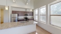 Located on Baldwin Street SE in Grand Rapids, Michigan, this two-story home offers a thoughtful blend of contemporary design and rustic architectural character. The main level is anchored by a well-designed kitchen featuring dark espresso cabinetry, granite countertops, stainless steel appliances, and a central island with an undermount sink. Soaring ceilings with exposed beam detailing and light hardwood flooring throughout the main level create an open, airy atmosphere, while multiple windows allow generous natural light and views of the surrounding neighborhood.

A half bathroom on the main level is finished with granite countertops, a modern vanity with light wood cabinetry, and large-format tile flooring. A full bathroom nearby mirrors the same refined finishes, with an extended vanity and adjacent space housing a stacked washer and dryer, providing convenient in-unit laundry access.

The upper level is a standout feature of this home, showcasing dramatic exposed timber trusses that lend a rustic, loft-like character to the space. Vaulted, angled ceilings rise overhead, and plush carpet flooring adds warmth underfoot. A cable-style railing lines the open staircase, reinforcing the modern aesthetic while maintaining sightlines across both levels. The upper floor offers versatile open space suitable for a variety of uses.
