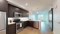 Located at 1540 Vine St in Hollywood, Los Angeles, this modern single-floor residence offers a clean, contemporary design throughout. The open-concept kitchen is a standout feature, outfitted with rich dark-toned cabinetry that extends to the ceiling, crisp white quartz countertops, a marble-style tile backsplash, and a full suite of stainless steel appliances including a gas range, built-in microwave, dishwasher, and refrigerator. Light wood flooring flows through the kitchen and living areas, complementing the bright, minimalist aesthetic. Pendant lighting over the kitchen adds a modern touch, while large windows invite abundant natural light into the living space, creating an airy and open ambiance. The bedroom features plush carpeting, a ceiling fan, and a generously sized window with views of the surrounding building exterior. A second carpeted room offers flexible use as an additional bedroom or office. The bathroom is finished with classic penny-tile flooring, a dark vanity with white countertop, and a large mirror, and connects directly to a dedicated walk-in closet. A smart home panel and keypad entry are also present, adding a layer of convenience and security to this well-designed Hollywood residence.