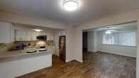 This two-story, 3-bedroom, 2-bathroom residence offers a functional and well-appointed layout across two levels. The main floor features an open-concept design connecting the kitchen and living area, both finished with durable wood-look flooring. The kitchen is equipped with white shaker-style cabinetry, light stone countertops, stainless steel appliances including a refrigerator and over-the-range microwave, and a peninsula that provides additional prep and dining space. A textured ceiling and flush-mount lighting complete the kitchen's clean aesthetic. The living area is bright and open, enhanced by a ceiling fan and access to natural light through slatted window blinds. A staircase with a handrail leads to the upper level, where the bedrooms are located. Each bedroom features plush carpeting, ceiling fans, and windows with blinds for natural light and privacy. One bedroom includes a walk-in closet with built-in shelving. The bathrooms are efficiently designed, with one featuring a glass-enclosed standing shower, a toilet, and a window for ventilation. Neutral wall tones and consistent finishes throughout create a cohesive and move-in-ready environment well-suited for comfortable everyday living.