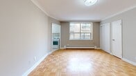 Located at 276 Saint Clair Avenue West in the heart of midtown Toronto, this efficiently designed unit offers a well-organized single-floor layout comprising a living room, kitchen, bathroom, and closet. The living room serves as the central space, showcasing classic parquet wood flooring in a warm honey tone, neutral grey walls, and crisp crown moulding that adds a touch of architectural character. A large window allows natural light to filter in, offering views of the surrounding neighbourhood, while a baseboard heater runs along the wall beneath it. The compact kitchen is thoughtfully appointed with white cabinetry, a marble-patterned countertop, a stainless steel sink, tiled backsplash, and includes a refrigerator and stove. The full bathroom features clean white tile work throughout, including a tiled shower-tub surround, a vanity with mirror, and white tile flooring, creating a bright and functional space. A dedicated closet provides convenient storage. The unit's clean, neutral palette and classic finishes create a practical and comfortable living environment in one of Toronto's well-connected midtown neighbourhoods.