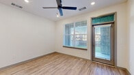 Located at 23683 W Yuma Rd in Buckeye, AZ, this well-designed one-bedroom, one-bathroom unit offers a clean, modern aesthetic with thoughtful finishes throughout. Wood-look plank flooring runs seamlessly across the entire floor plan, complementing the crisp white walls and creating a cohesive, contemporary feel.

The open-concept kitchen and living area serves as the heart of the unit. The kitchen is a standout feature, boasting a two-tone cabinet design that pairs white upper cabinetry with warm wood-toned lower cabinets and a matching center island. Light quartz countertops, a marble-style tile backsplash, stainless steel appliances — including a French door refrigerator and over-range microwave — and matte black hardware complete the space. Stylish geometric pendant lights hang above the island, adding an elegant touch.

The living area is bright and airy, benefiting from a large window with blinds and a ceiling fan with recessed lighting overhead. A private entry door with a transom window adds natural light and outdoor access.

The spacious primary bedroom features its own ceiling fan, a large window with outdoor views, and a double-door closet for ample storage. The bathroom offers a wood-toned vanity with white countertop, white cabinetry, and wood-look flooring, maintaining the unit's consistent modern style throughout.